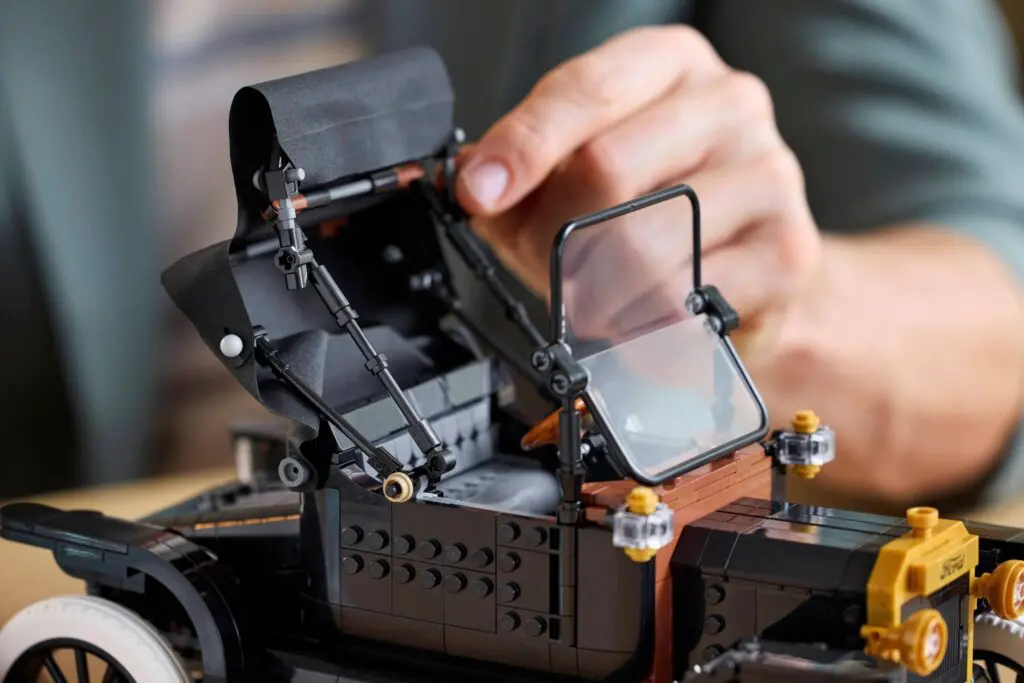 Hands constructing miniature antique vehicle