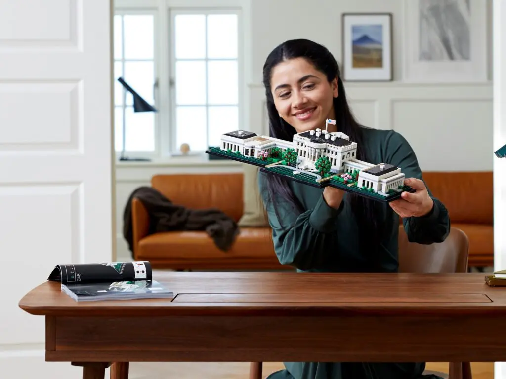 Smiling woman displays building model indoors