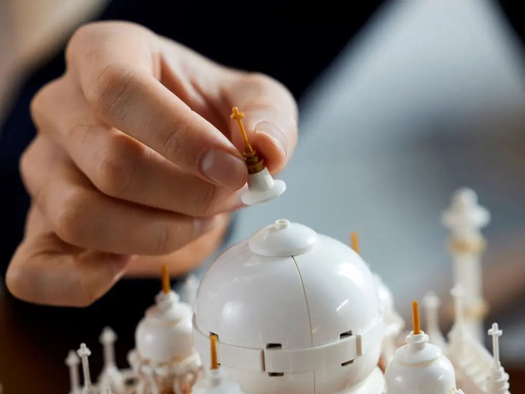 Hand placing piece on white building model.