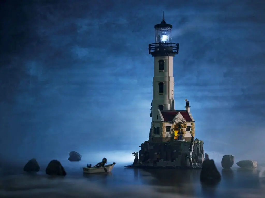 Illuminated lighthouse surrounded by rocks