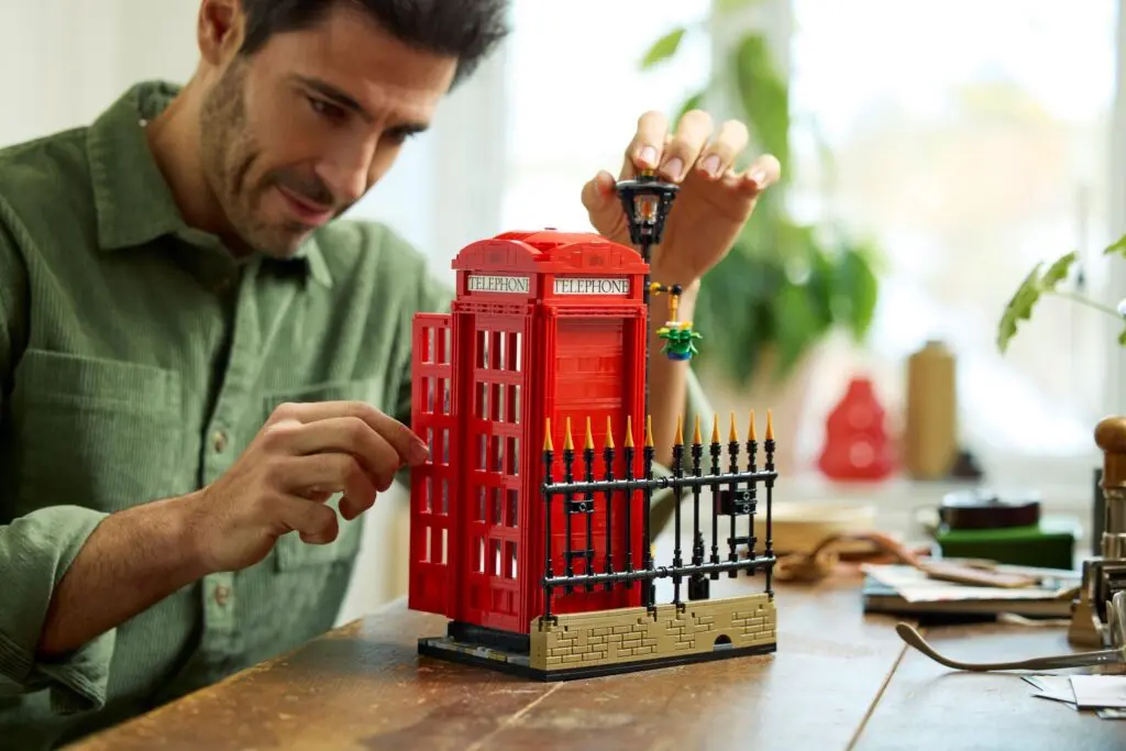 Man assembling red LEGO building set