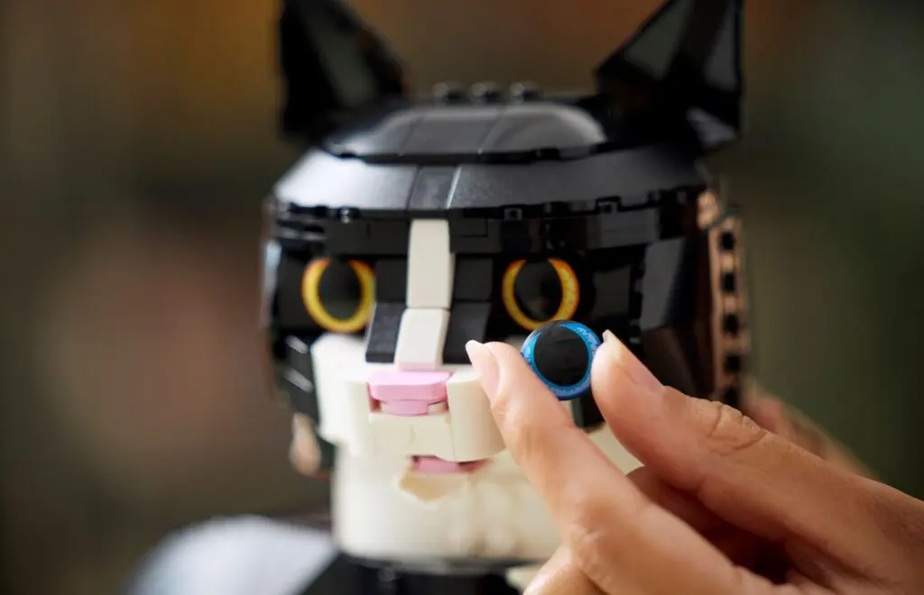 Lego cat head with hand adjusting eye.