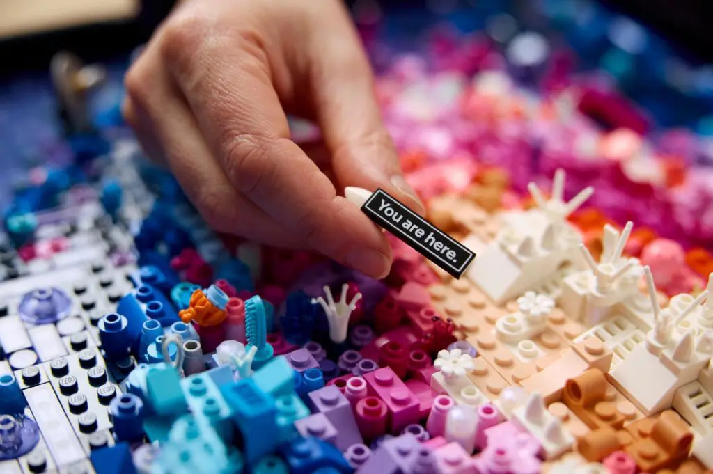 Hand placing "You are here" sign in Lego