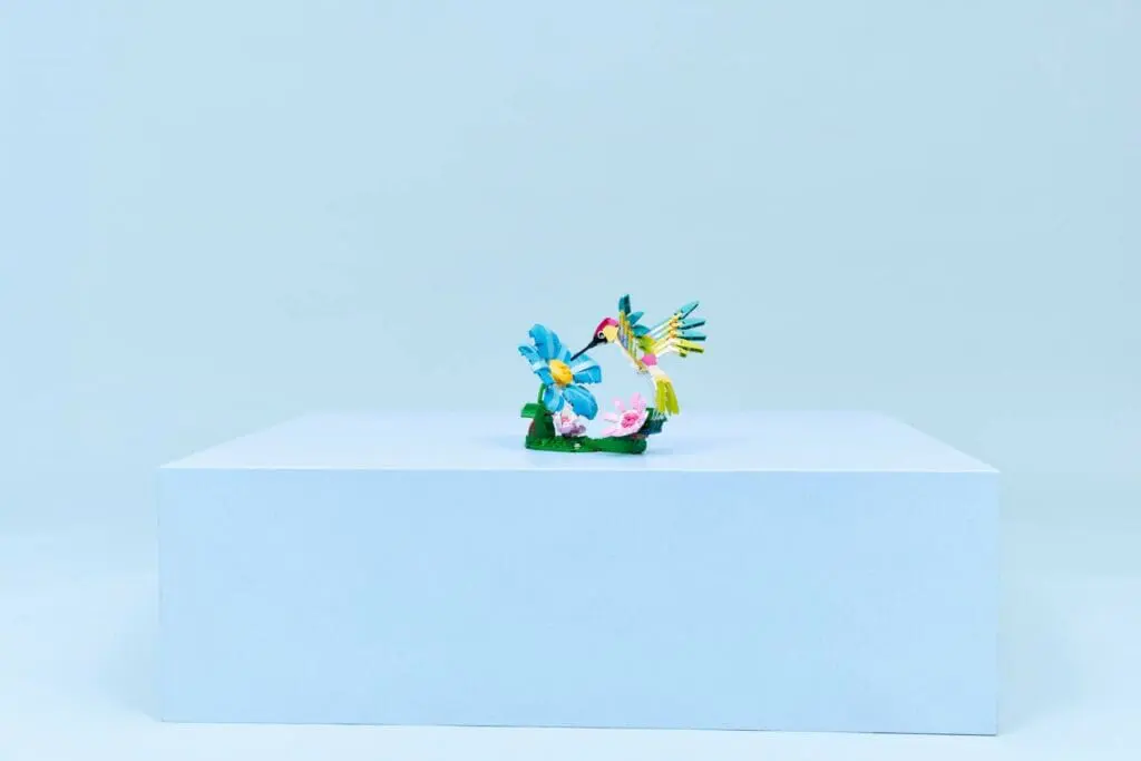 Colorful bird figurines on white pedestal