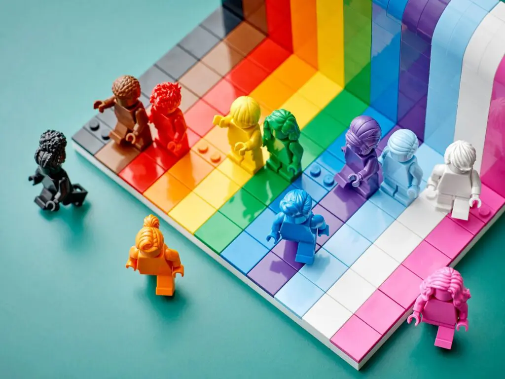 Lego figures ascending rainbow-colored steps