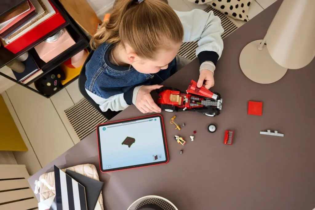Girl building red model car on table