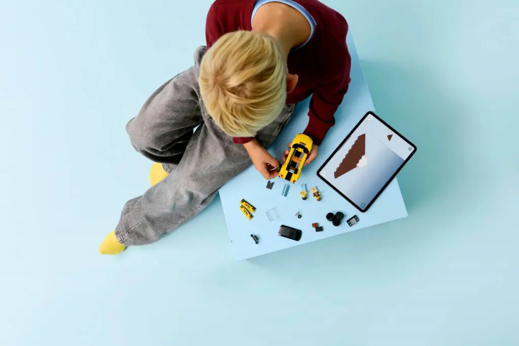 Kid playing with construction set and tablet