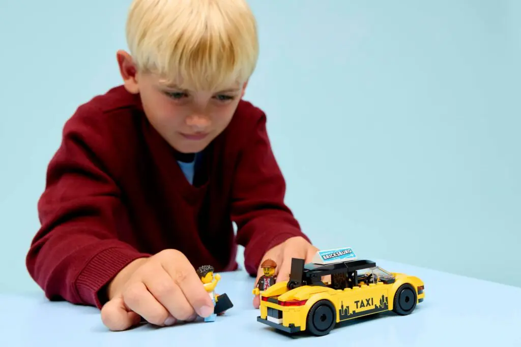 Child playing with toy taxi and figures.