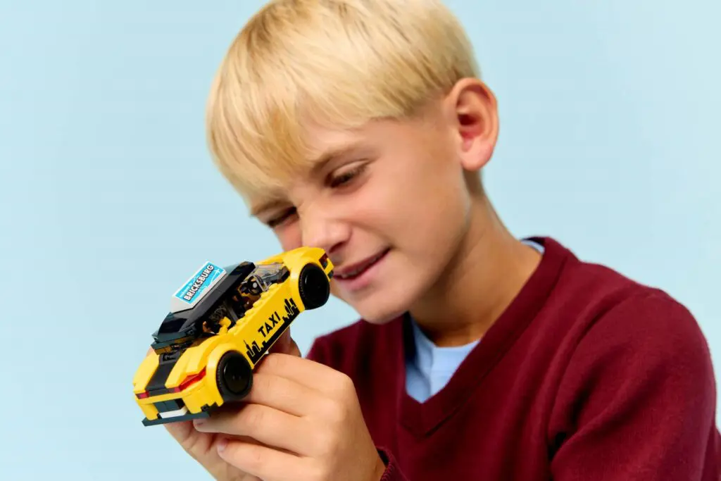 Boy examining small yellow taxi toy