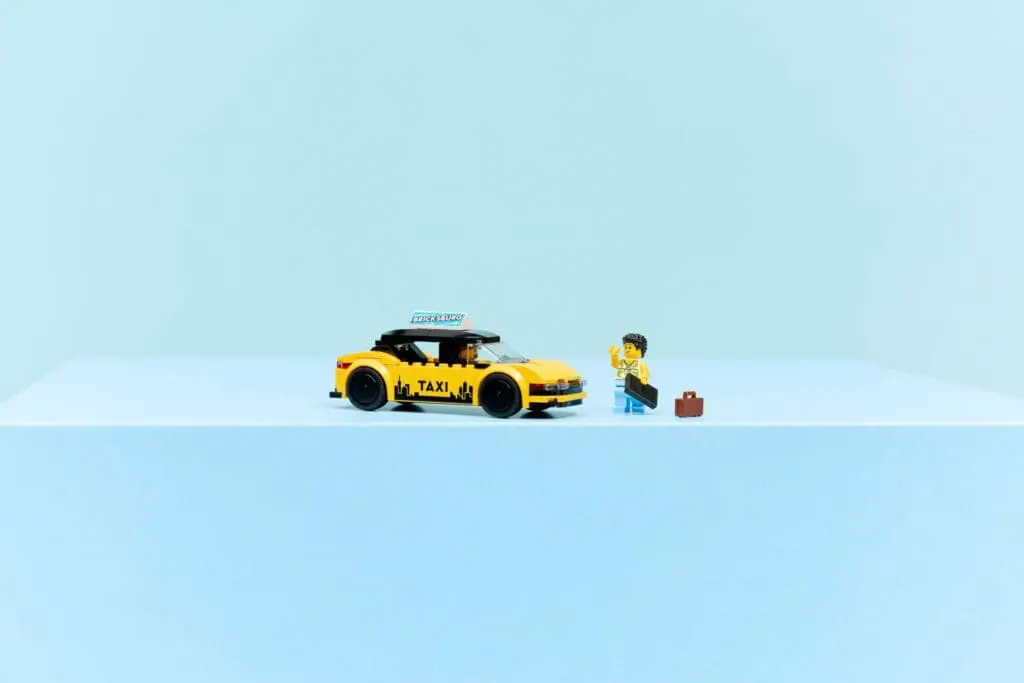 Lego-style taxi and traveler with suitcase