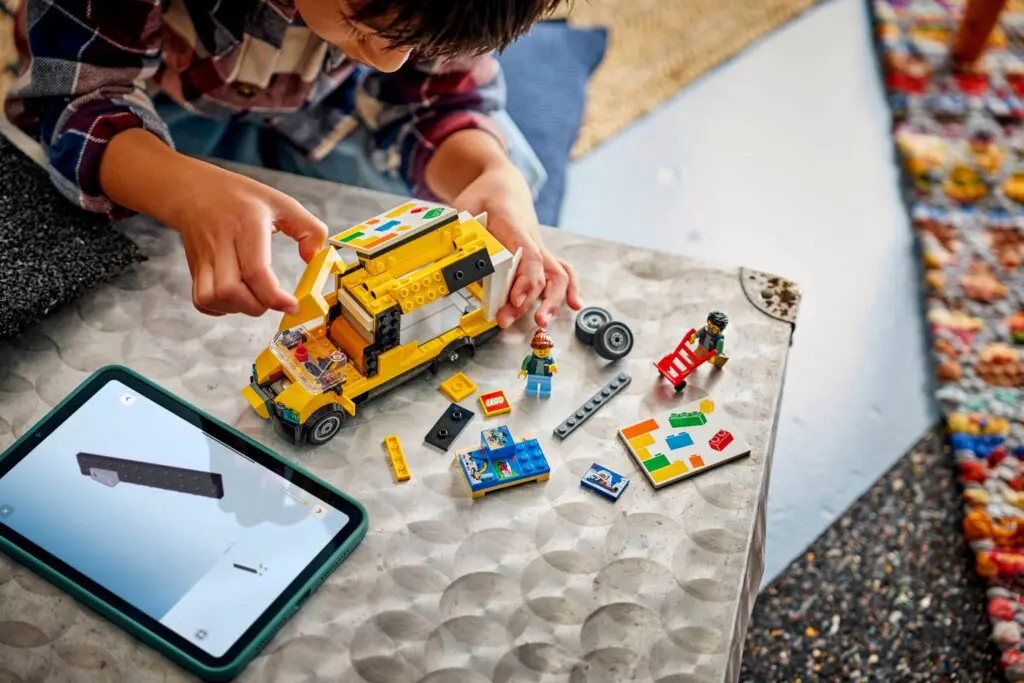 Child building with LEGO and tablet instructions.