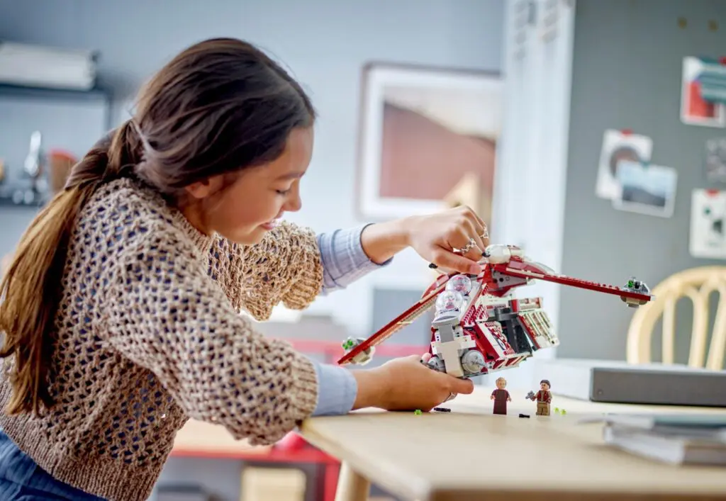 Girl assembling red toy spaceship.