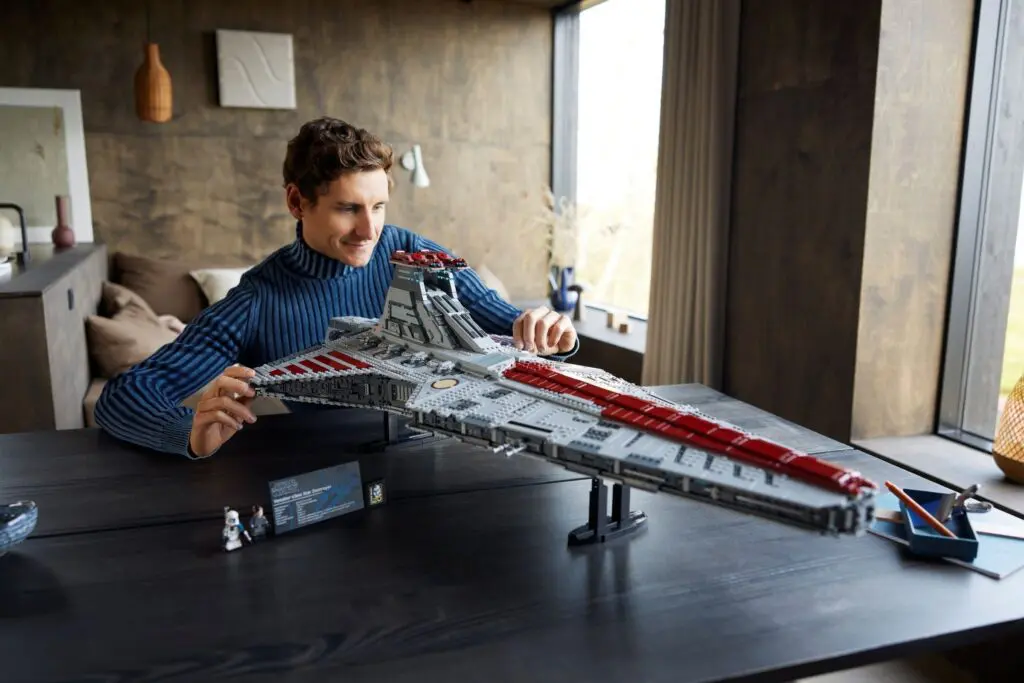 Man assembling large spaceship model on table.