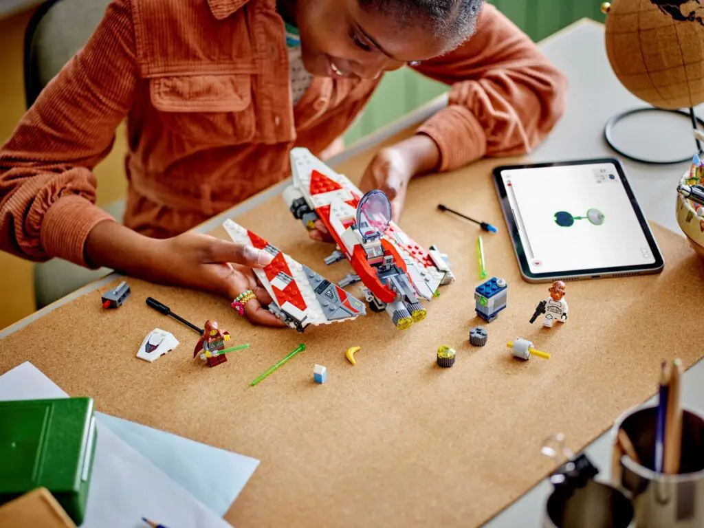 Child assembling spaceship model with tablet