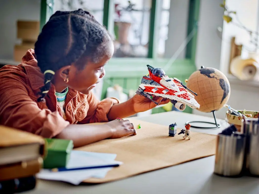 Girl holding model spaceship, globe nearby