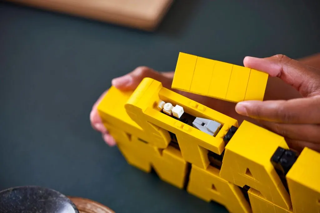 Person building yellow LEGO block structure.
