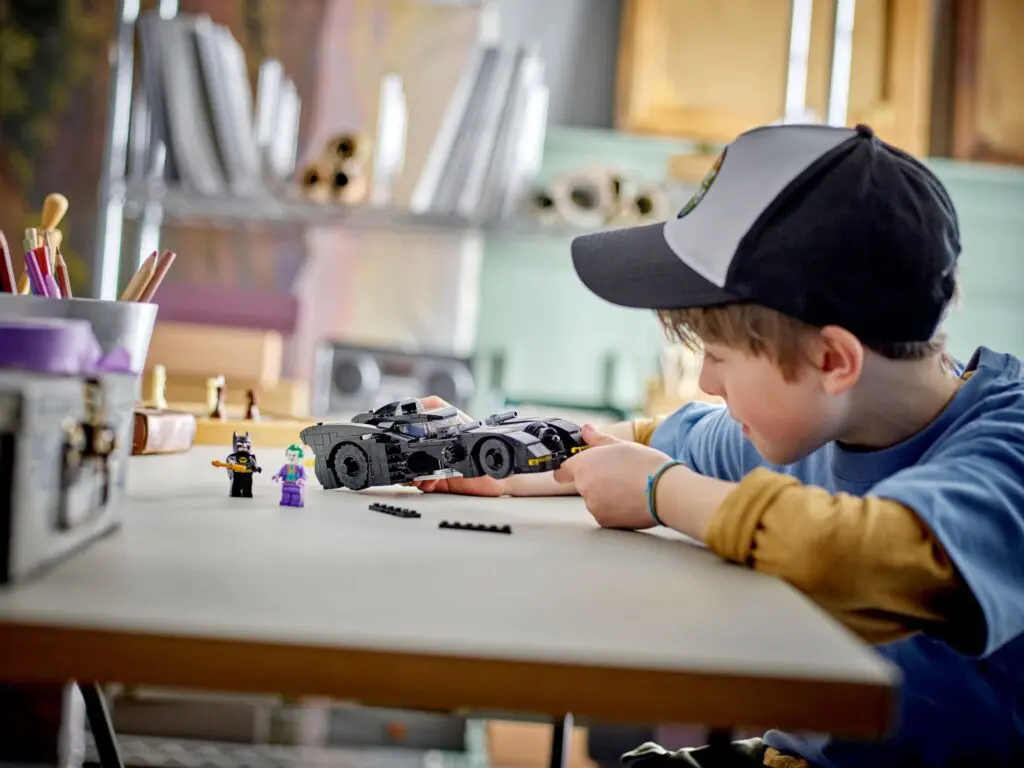 Boy in cap assembling toy car.