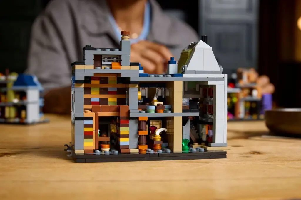 Person assembling LEGO structure in background