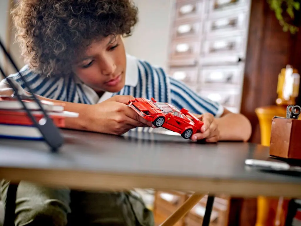 Boy examining miniature red sports car
