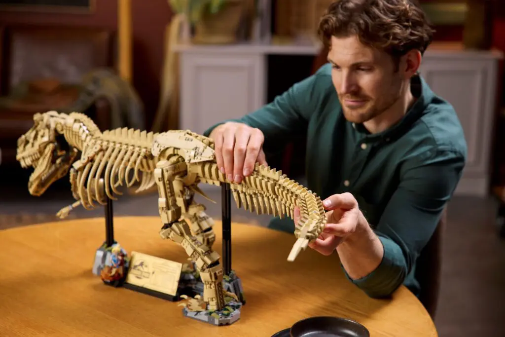 Person building dinosaur model on table