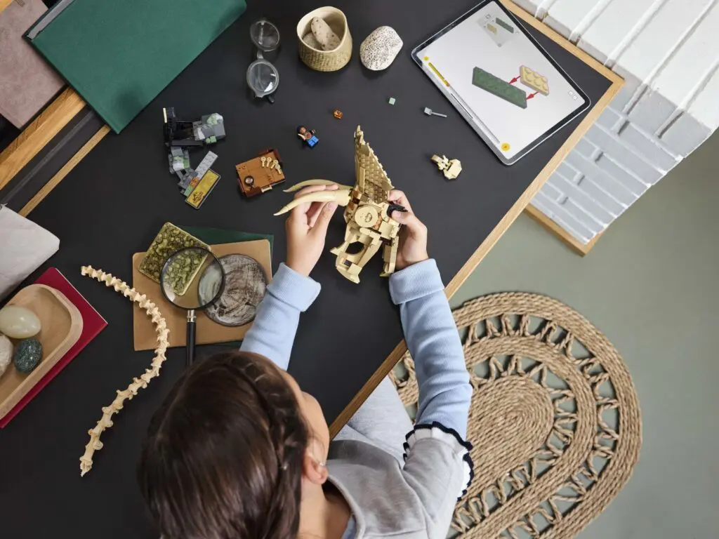 Child assembling dinosaur model at desk