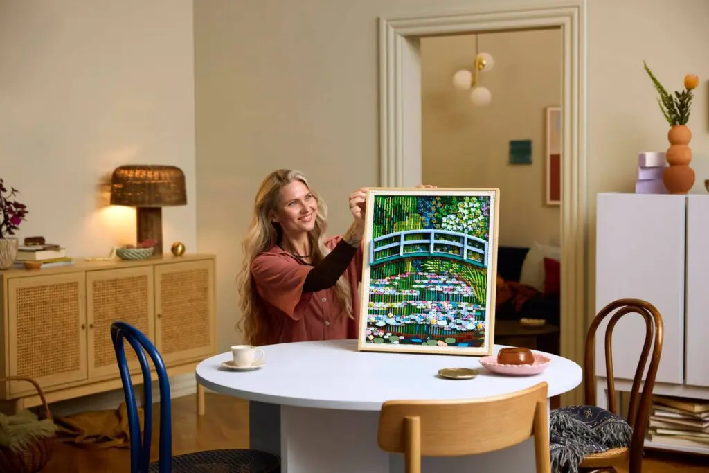 Woman holding framed painting in cozy room