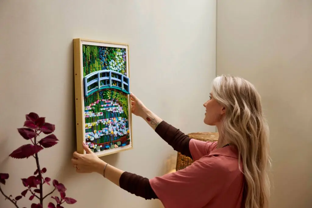 Woman hanging framed painting on wall