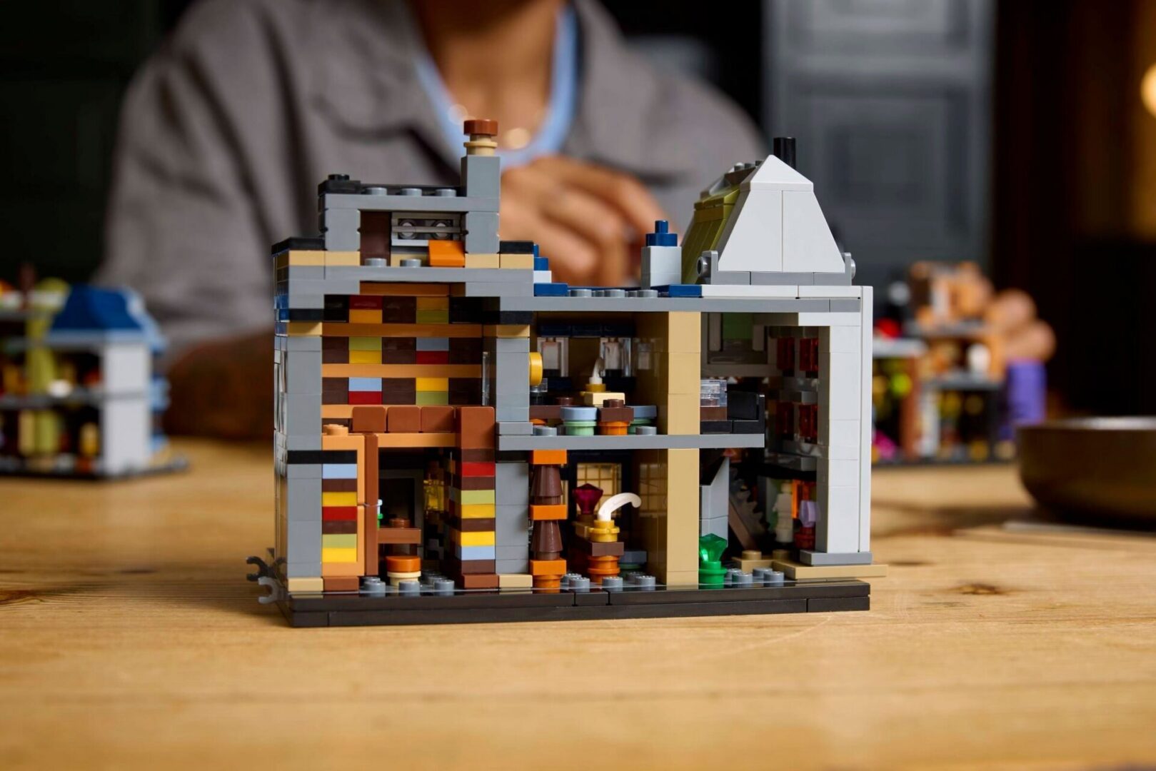 Person assembling LEGO structure in background